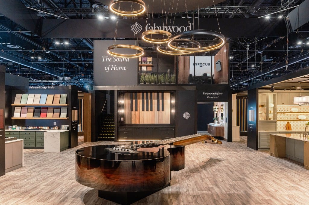 The Fabuwood KBIS booth featuring The Sound of Home display, ring chandeliers, piano-key wall, and Design Studio samples.